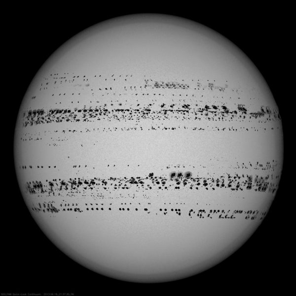 A grey orb against a black background with hundreds of black dots that form lines in the upper- and lower-middle portions