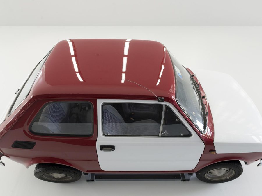 a red and white fiat hanging from a gallery wall