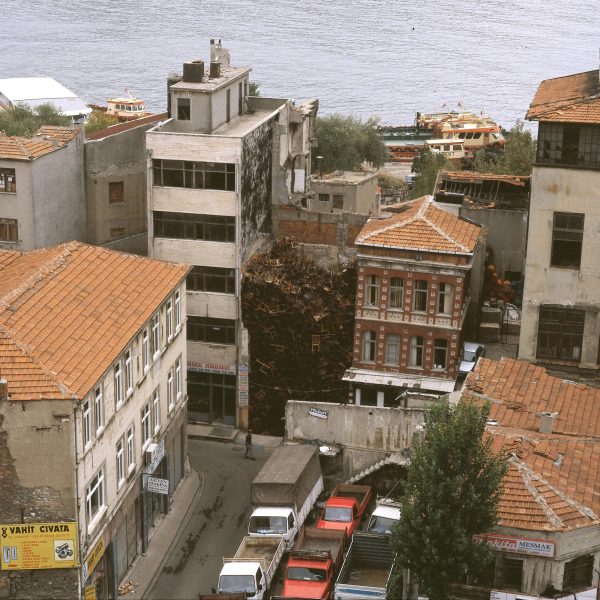 Overhead view of old buildings near a body of water. Between two buildings is a pile of chairs three stories high.