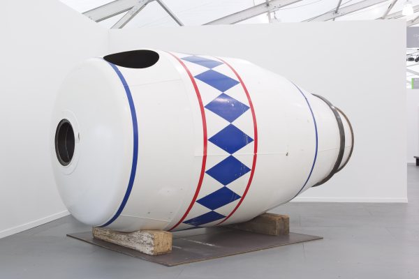 An installation view of a large white container decorated with red and blue designs