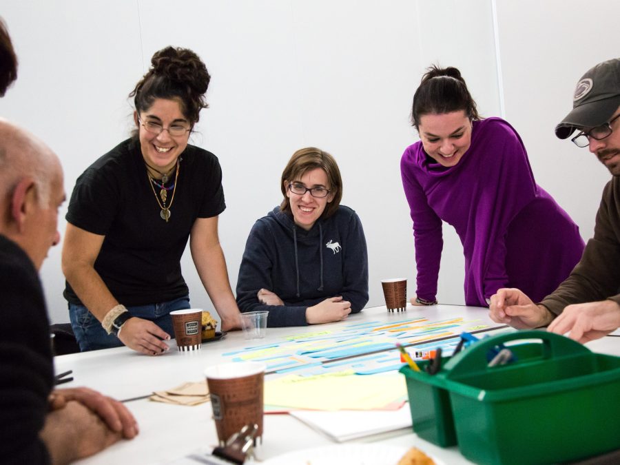 A group of adults gather around a table with disposable coffee mugs and art-making supplies