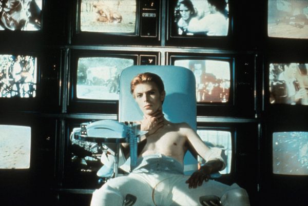 David bow in a teal chair with four rows of four video screens
