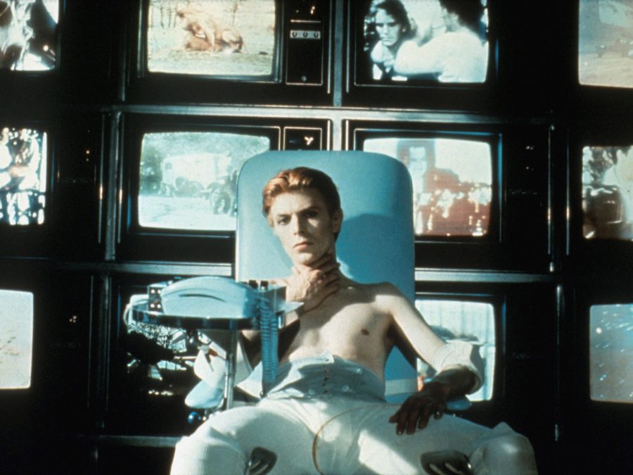 David bow in a teal chair with four rows of four video screens