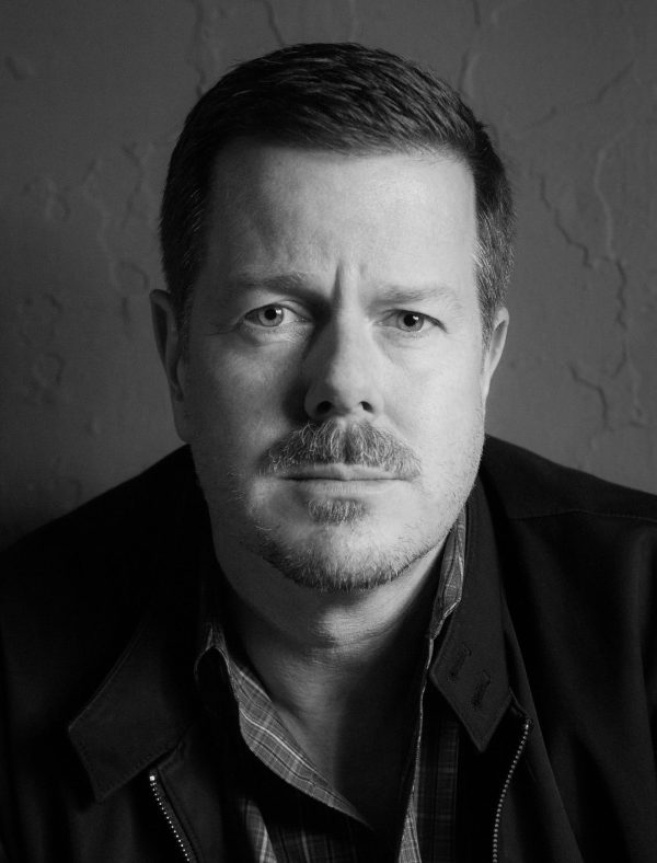 Black-and-white portrait of a man with a goatee looking directly at the camera