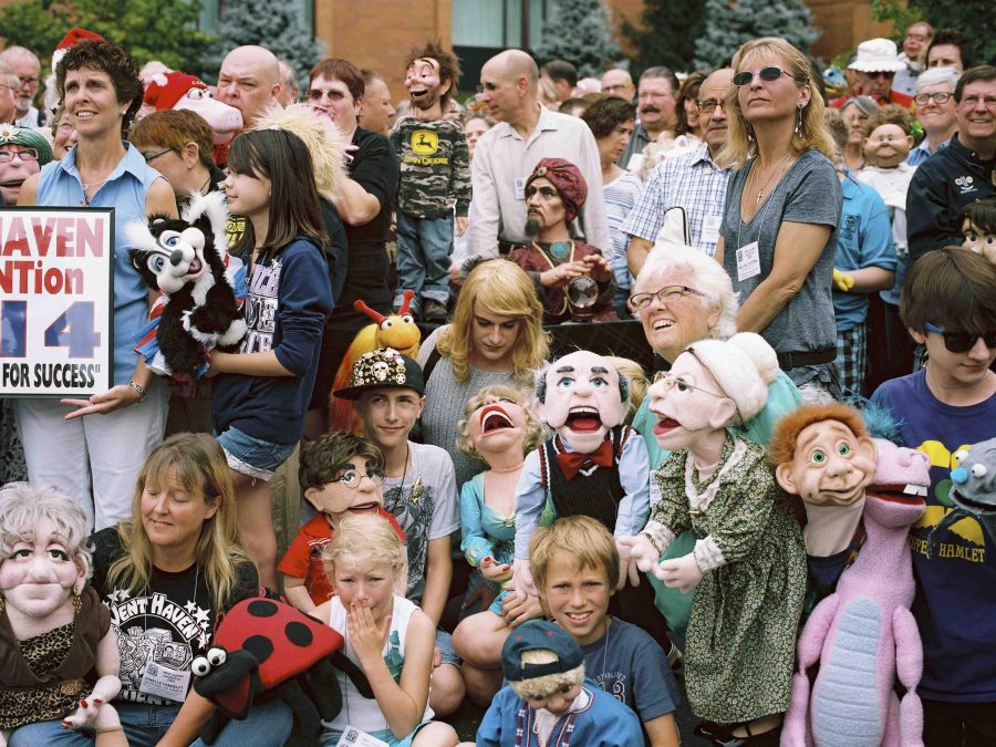Group photograph of seated and standing people and kids holding various ventriloquist dummies
