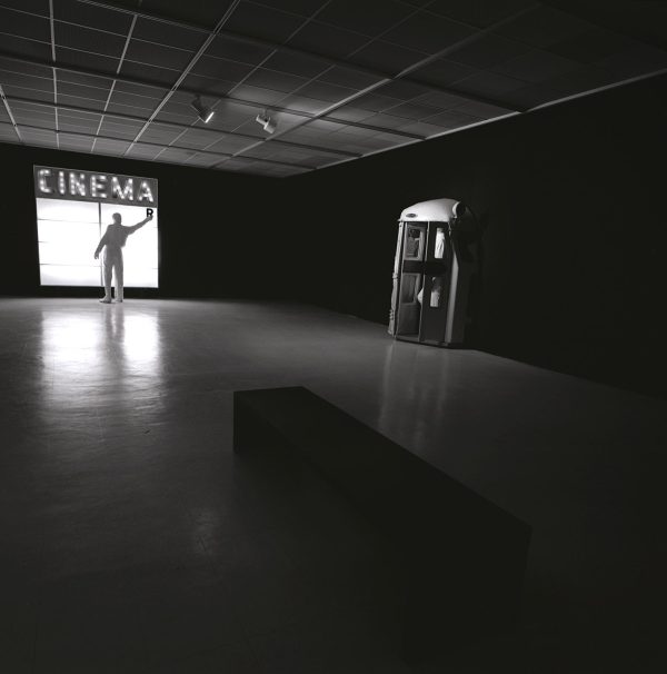 In a dark room a figure changes the letters on a cinema sign