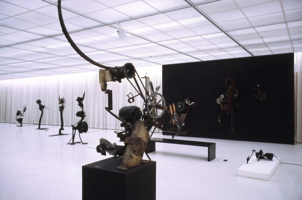 Photo of sculptural installations in a gallery space with office-like neon lighting overhead