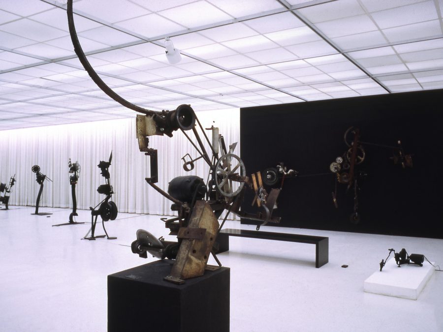 Photo of sculptural installations in a gallery space with office-like neon lighting overhead