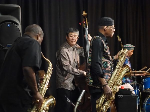 Jazz musicians performing on alto and tenor saxophones, string bass, and drums