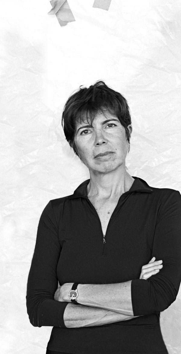 Black-and-white portrait of a short-haired woman, arms crossed, in a black zippered top