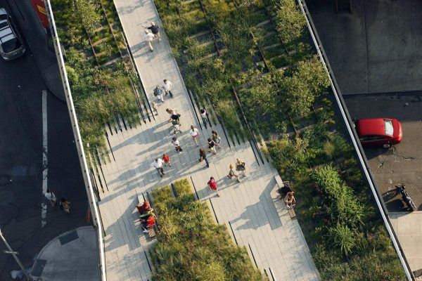 Aerial view of a linear, raised boardwalk with greenery and a handful of people