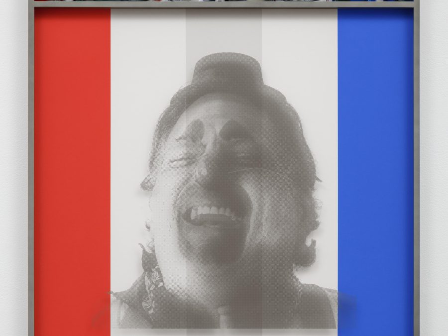 A black and white image of a laughing clown appears on a panel of red, white, and blue vertical stripes inside a gray frame. Inside the frame, above the image, a cubbyhole is filled with holiday lights and campaign buttons in red, white, and blue sections that mirror the stripes below.