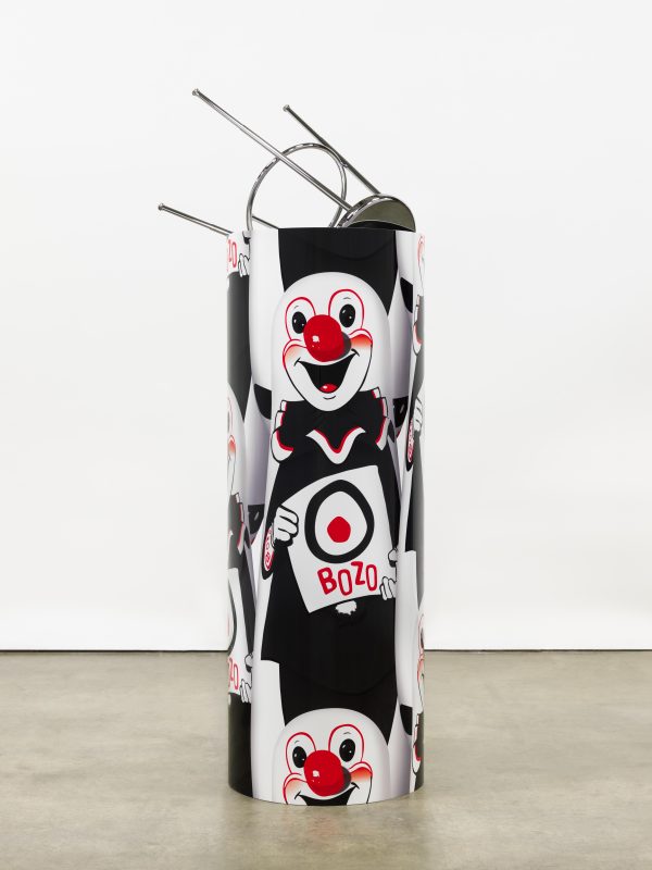A cylinder is wrapped with the repeating image of a white, red, and black clown holding a target with 