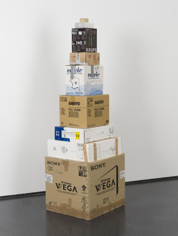 Nine shipping boxes of various shapes and sizes stacked from widest on the bottom to slimmest on top