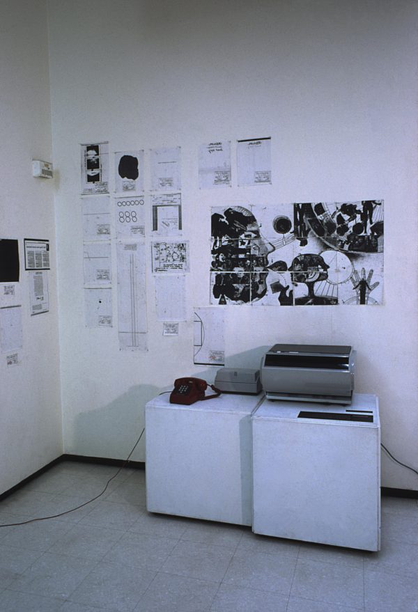 A telephone and a printer on two white blocks in the corner of a room filled with printouts on the white wall above