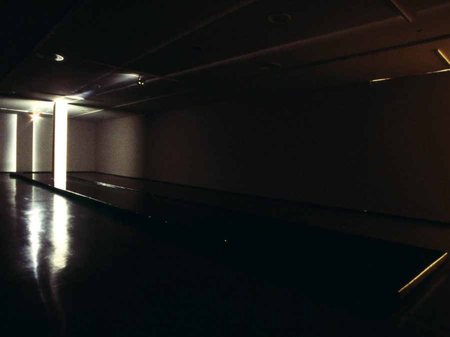 A spotlight highlights a white pillar in the back corner of an otherwise dark room