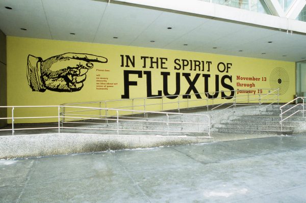 A photograph of the MCA's former location on Ontario street with a banner that shows a large illustrated hand pointing at large text 