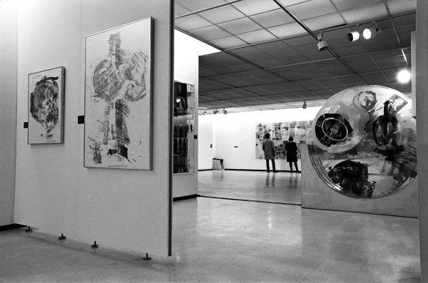 A black-and-white photo of a partial installation view shows a sculpture and multiple other graphic artworks.