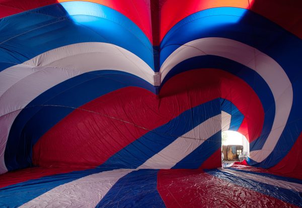 A view from inside a red, white, and blue striped hot air balloon out toward the basket, tipped on its side