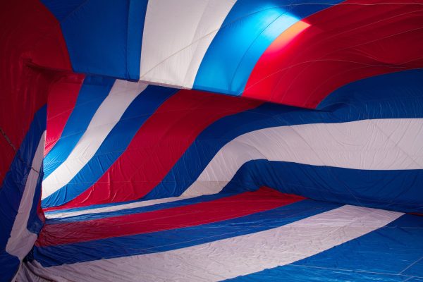 A red, white, and blue fabric canopy presses against the walls of a room. Light enters the room through a door at the back on the left side.