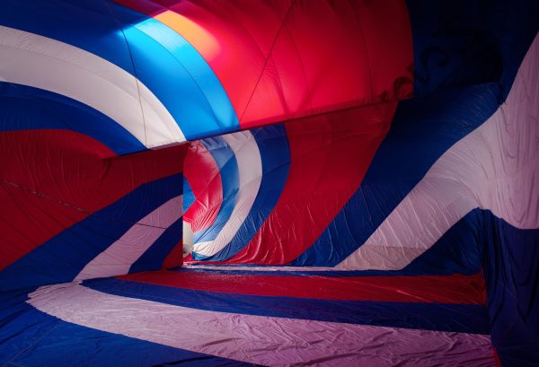 A red, white, and blue fabric canopy presses against walls of room. Light enters the room through a door at the rear.
