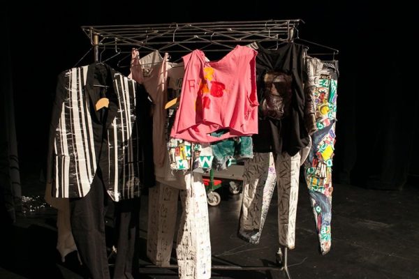 Costumes hanging on a clothes rack in a room with black walls