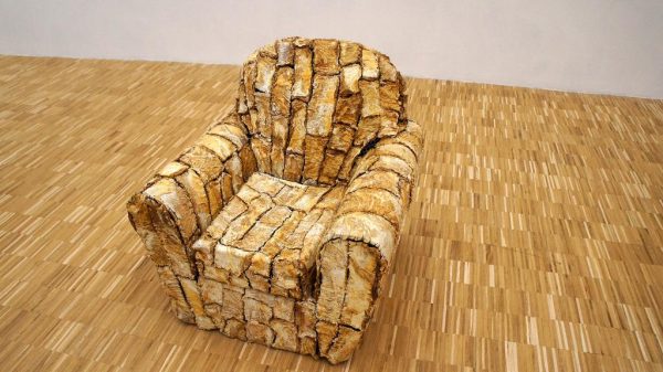 A sofa chair covered in brown slices of meat viewed from slightly above. The carpet appears to be the same color.