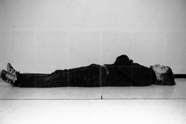 A man lying on the floor underneath a sheet of glass.