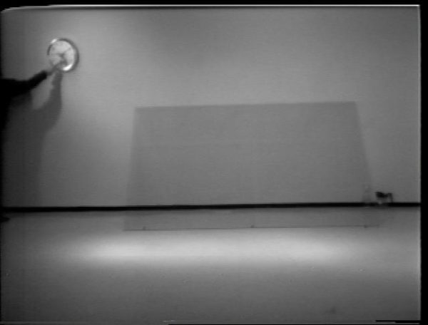 Grainy video still of a man smashing a wall clock