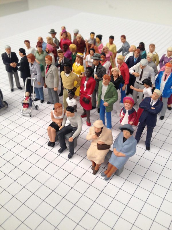 Six rows of colorful figurines of men, women, and children on a floor with a grid of black-and-white squares
