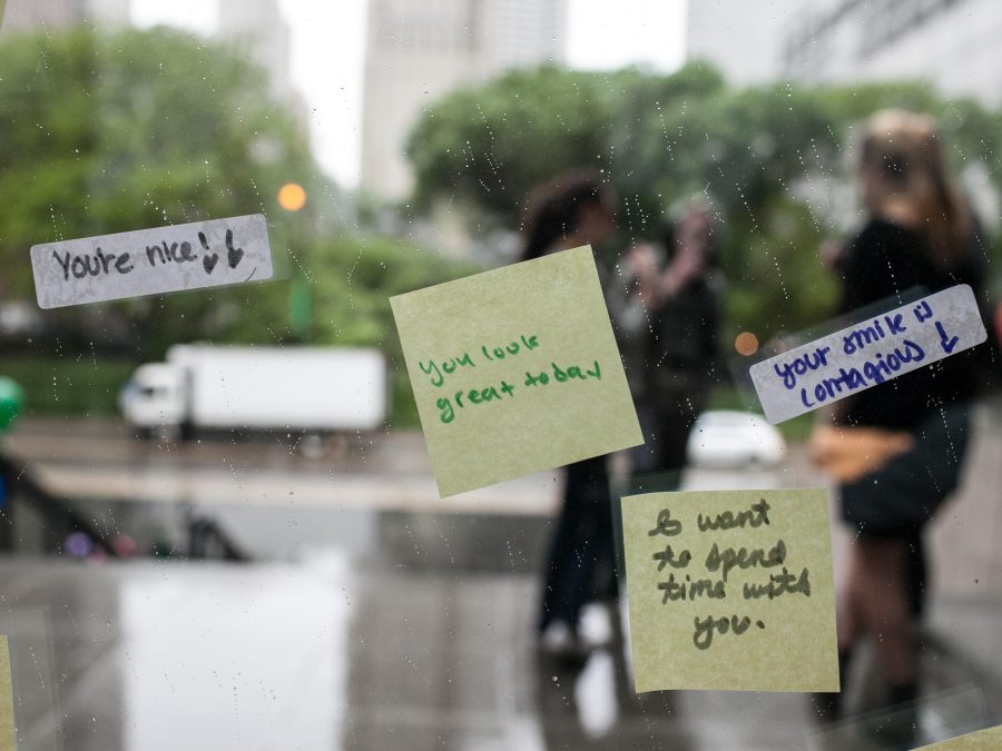 Post-It notes and stickers with complimentary phrases are stuck to a window looking out at people on the MCA's front staircase.