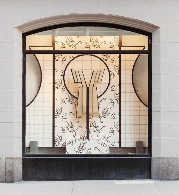 A black and white 1920s style window display featuring a white dress with black vertical stripes