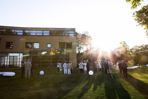 Late afternoon picture of a group of people gathered outside a large, modern home.