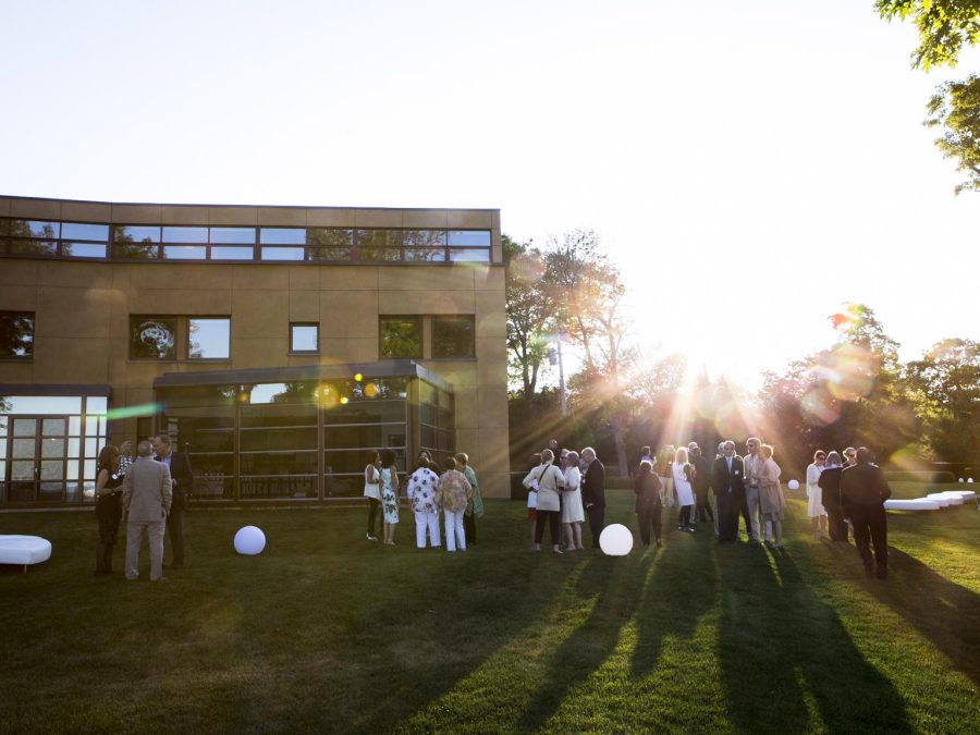 Late afternoon picture of a group of people gathered outside a large, modern home.