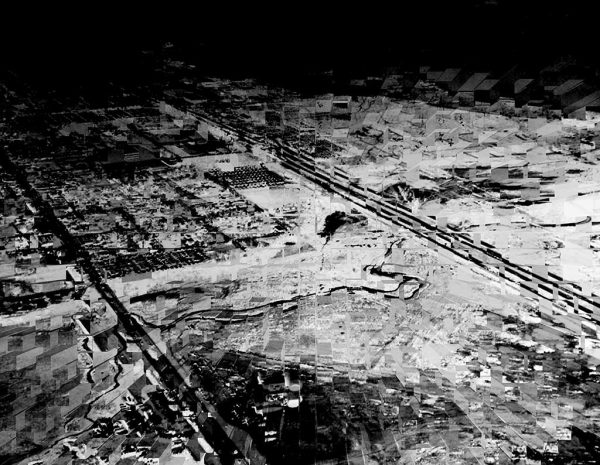 A black and white aerial photograph of several different housing developments and fields