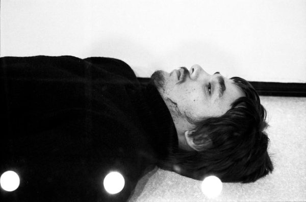 Close up of the face of a man lying on the floor with lights reflected on him