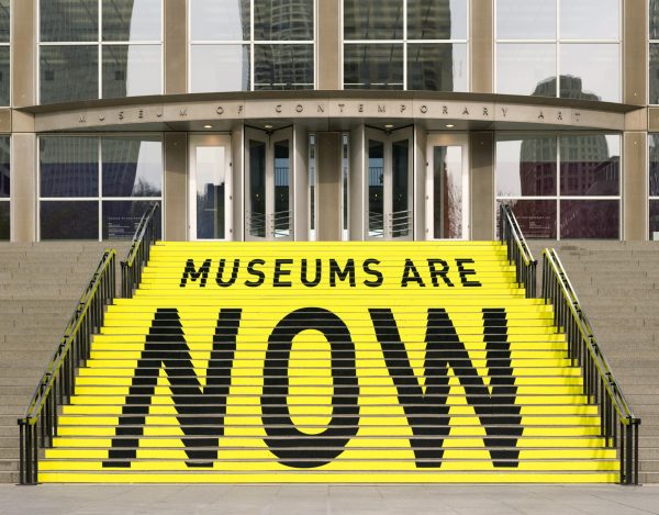 The stairs leading to the MCA's entrance are painted yellow with black text that reads, in smaller letters: 