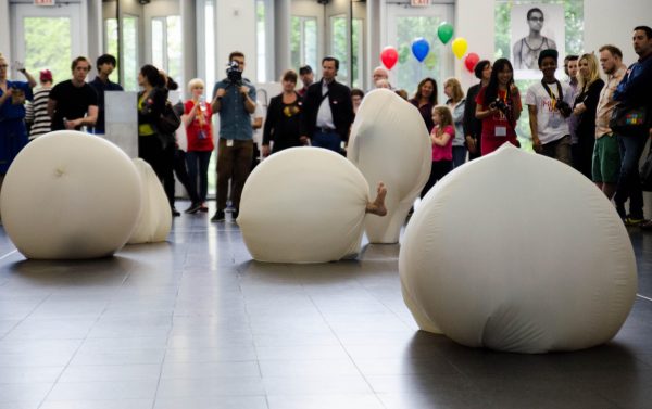 Feet stick out of four large white balls as a crowd looks on