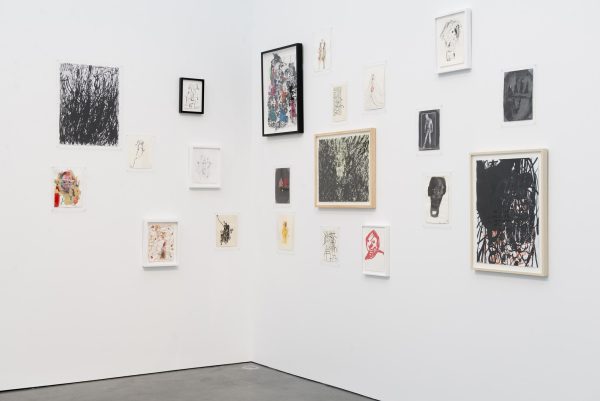 Corner of a white gallery space with various sized artworks hanging
