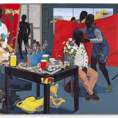 A black woman poses in a chair against a vivid red backdrop while a woman adjusts her head and a man gets dressed behind the backdrop. The painted portrait in progress is shown on an easel at left, next to a table strewn with paints and paintbrushes, a skull, and vase with flowers. A yellow dog rests on the floor below the table. A nude figure stands in the background.