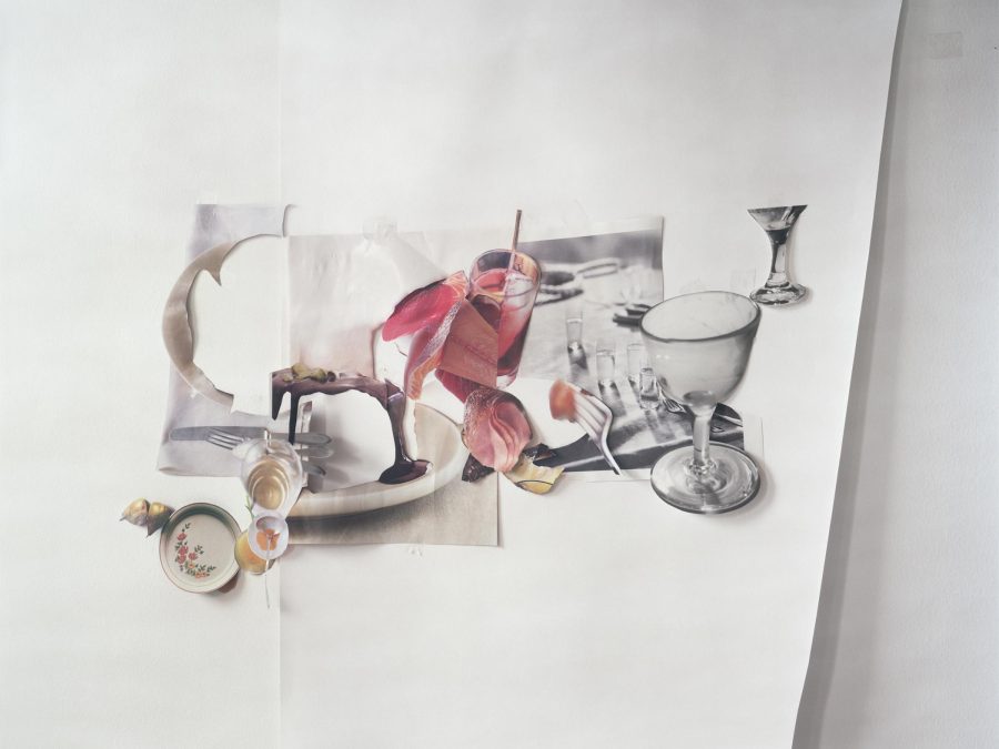 Cutouts of glasses, silverware, and plates of food form a place setting on a sheet of white paper