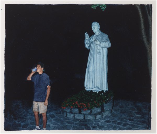 A person drinks next to a saint's statue that is posed in making a blessing motion with their hands at night