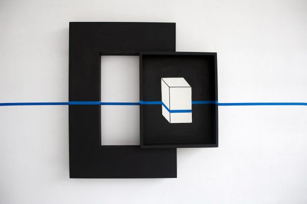 A black box containing an image of white box is mounted on the side of a thick black frame. The entire piece is intersected by a horizontal blue line, which appears to be painter's tape.