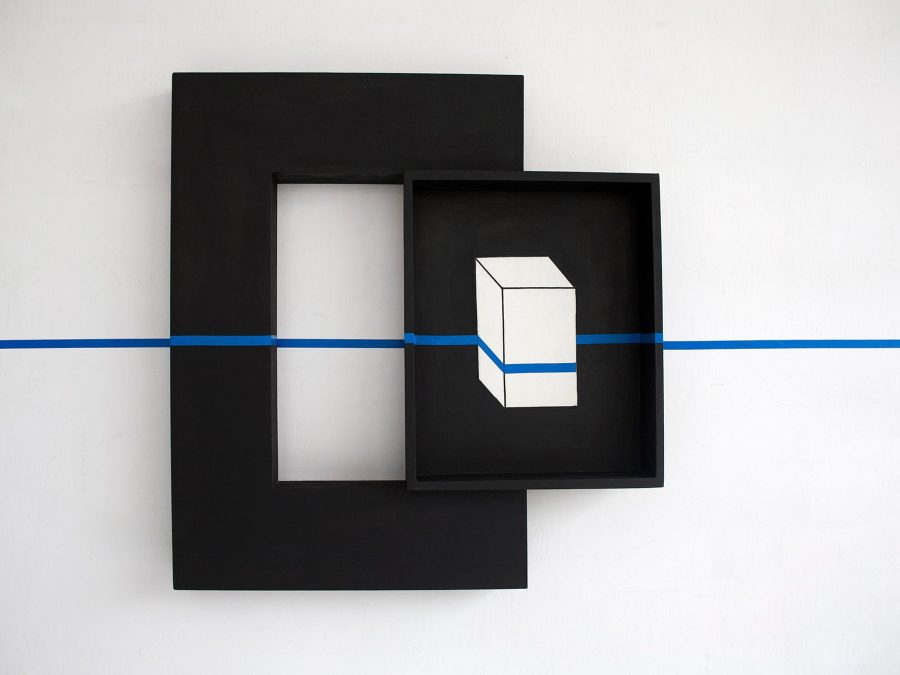 A black box containing an image of white box is mounted on the side of a thick black frame. The entire piece is intersected by a horizontal blue line, which appears to be painter's tape.