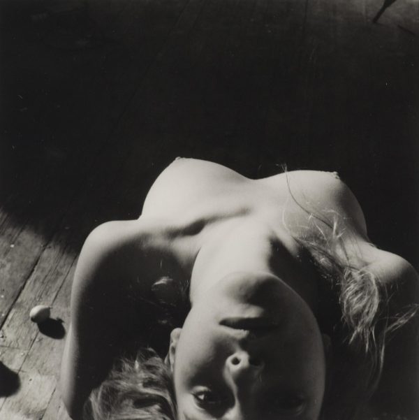 Black and white photograph of a nude female with their head tilted back as viewed from above