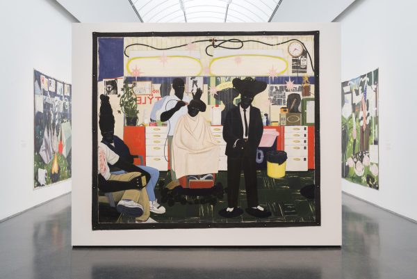 A colorful painting displayed in a white, barrel-arched gallery. The artwork depicts a lively barbershop scene with several people engaged in various activities. The background features bright, patterned walls and a clock. The painting is surrounded by other artworks on the gallery walls.