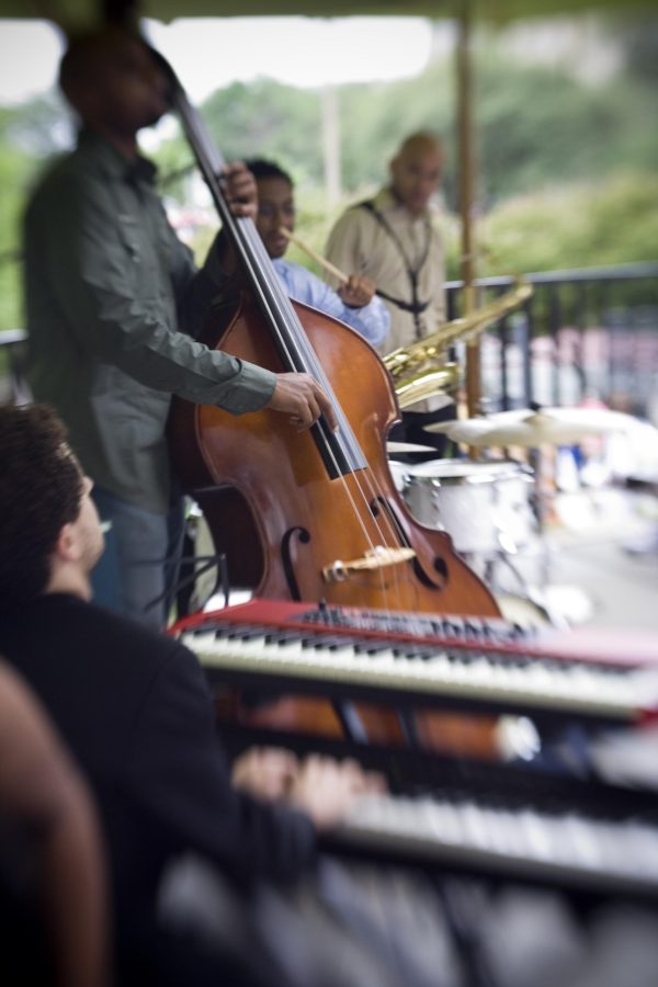 Closeup of a band playing in a row, the keyboardist in the foreground followed by the bassist and the drummer
