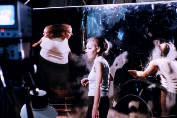 A woman's reflection is contorted and duplicated in a mirror
