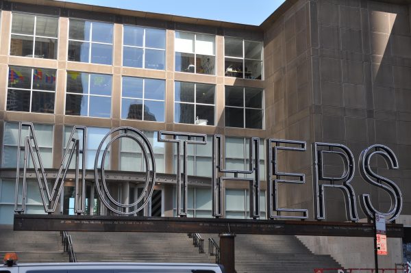 The word mothers spelled out in neon letters on a large metal stand in front of the MCA's front steps