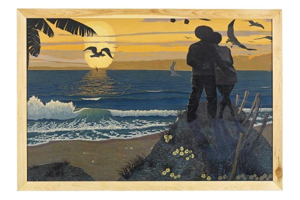 Two people stand with arms around each other while looking at a soft orange sunset on the beach. Waves hit the shore as birds fly above.